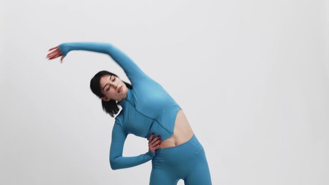 Fit young woman performing workout routine on white isolated background. Wellness, fitness and body care concept.