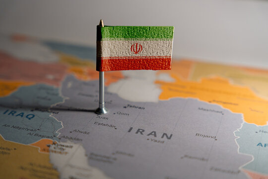 Iran flag pinned on political map over Iran in Middle East region. . Public domain World political map background. Source: CIA World Factbook (Public Domain).