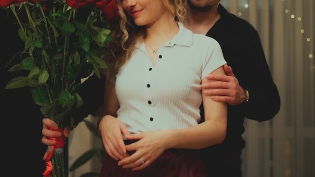 man hands holding gives gift bouquet flowers red roses to woman. Happy couple in love on Valentine's Day. guy comes on date with girl. cozy room. husband apologizes asks offended wife for forgiveness.