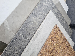 Fototapeta premium Various textured surfaces including gray marble, light marble, and cork. The materials are arranged in a layered fashion, showcasing their unique patterns and colors.