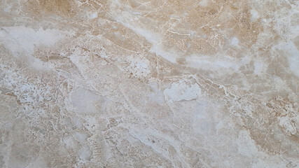 Obraz premium Close-up of a textured surface with a light beige color. The surface features subtle patterns and variations, resembling natural stone or marble. copy space