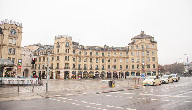 Pedestrians walking across Karlsplatz (Stachus) with historic architecture and storefronts in central Munich, capturing everyday city life in winter, February 01, 2026, Munich, Bavaria, Germany