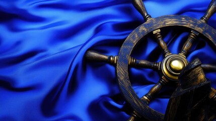 Vintage wooden ship wheel resting on flowing dark blue fabric with subtle textures and highlights