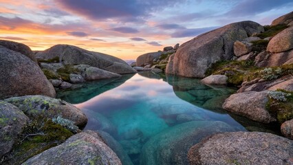 Serene alpine pool with crystal clear water reflecting a vibrant sunset sky amidst rocky terrain