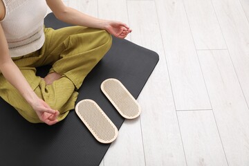 Fototapeta premium Young woman with sadhu boards meditating on yoga mat at home, closeup. Space for text