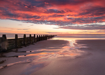 Fototapeta premium Sunrise and colourful morning light on Blyth Beach on the coast of Northumberland, England, UK.