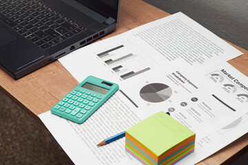 Obraz premium Office workspace with laptop, calculator and market analysis documents
