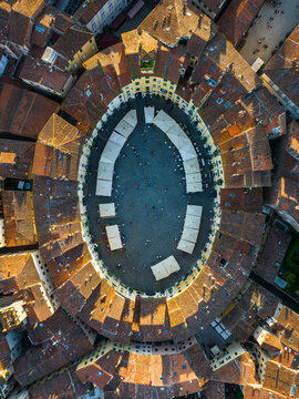 Aerial view highlighting the unique architecture of Piazza Anfiteatro in Lucca. The oval-shaped square preserves the footprint of a Roman amphitheater surrounded by historic buildings