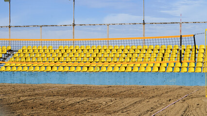 Fototapeta premium Yellow seating area with volleyball net at sandy beach sports venue
