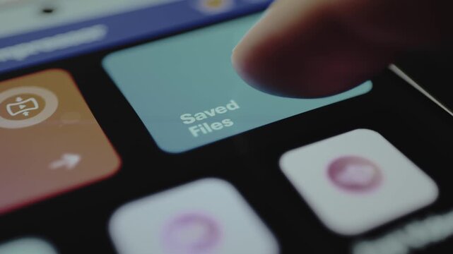 Finger taps the app button labeled Saved Files