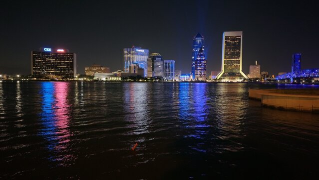 Aerial view of buildings light up the night sky, reflecting off the dark waters of the river, showcasing the city's vibrant skyline, Jacksonville, Florida, United States.