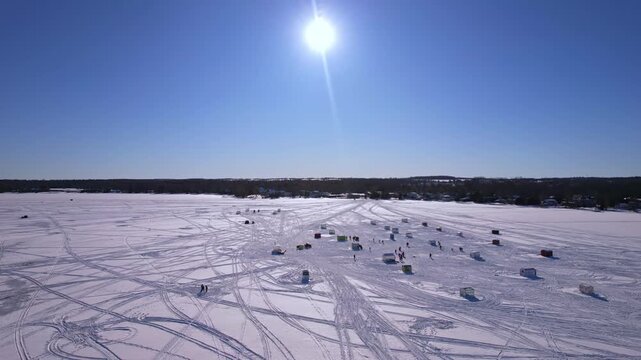 Snowmobile ski fresh tracks and fishing huts on frozen lake Simcoe, Cook&rsquo;s Bay, Innisfil, Ontario Canada, winter travel adventure concept and family fun during ice fishing season. Fishing charters.