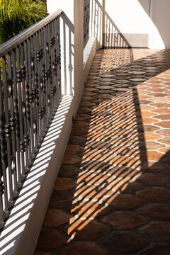 contrasty shadows of railing on Spanish-style orange tile floor