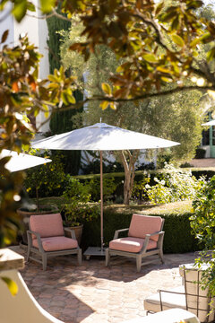 outdoor patio seating with umbrella, orange tile floor, blurry foreground looking through tree