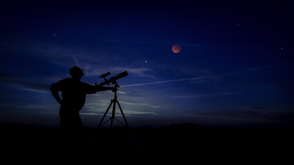 Amateur astronomer using telescope for watching stars, Moon, planets and other celestial objects from a field in nature. © astrosystem