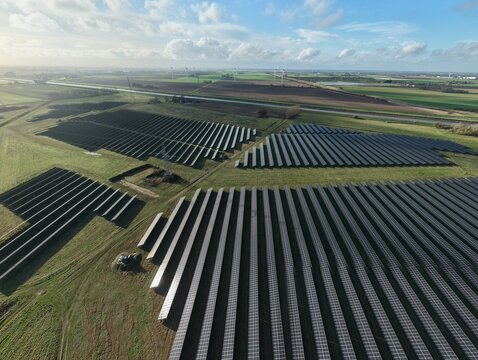 Aerial view of solar panels basking in the sun's embrace, a symphony of technology and nature, painting the landscape with shadows and light, Sutton Bridge, United Kingdom.