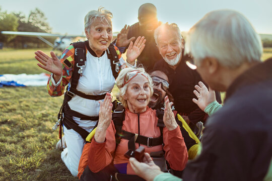 Senior friends celebrate skydiving landing at airfield