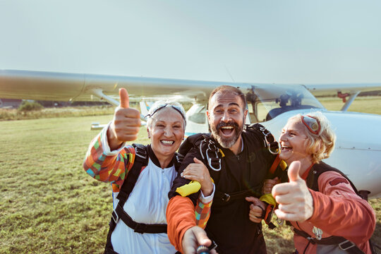 Happy senior friends taking skydiving selfie at airfield