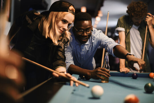 Young friends playing pool together at a bar