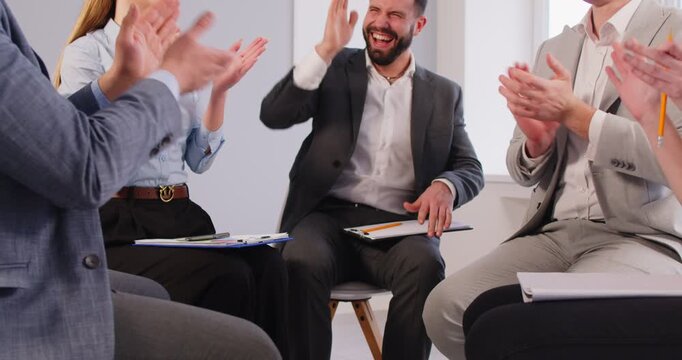 Close-up of business people in a team applauding and holding hands together in a circle during an office meeting, focusing on teamwork and group collaboration with unity and support.