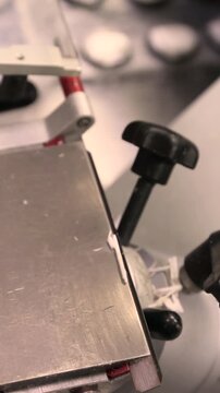 Close up of microtome device cutting precise thin tissue sections Prepared slices placed on glass slides for microscopic examination Illustrates laboratory workflow and histology sample preparation 