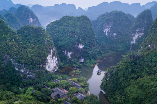 Aerial view of a serene landscape where emerald peaks meet tranquil waters, amidst the ancient beauty of Trang An, Hoa Lu, Vietnam.