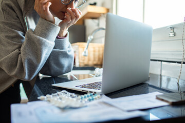 Worried person checking medical bills online at kitchen counter