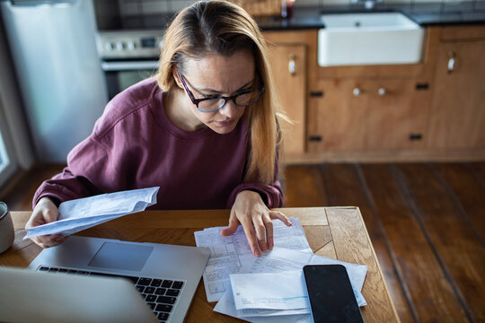 Woman reviewing household bills at home kitchen table