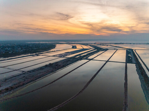 Aerial view of the vast salt pans reflecting the pastel hues of the setting sun, creating a surreal landscape of geometric patterns, Sambhar, Rajasthan, India.