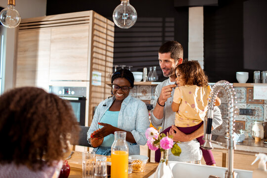 Smiling parents preparing breakfast with children in modern home kitchen
