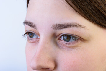 Naklejka premium Young girl after treatment, eyebrow correction on gray background.