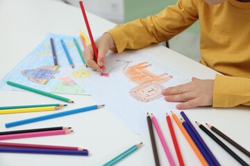 Little boy drawing lion with pencil at table, closeup