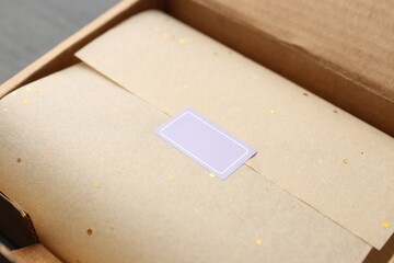 Cardboard box with packaging and blank sticker on black table, closeup