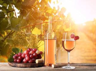 Naklejka premium Wine and fresh grapes on table. Glass and bottle in sunny vineyard