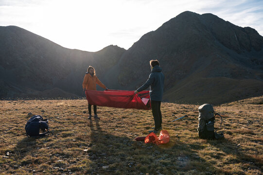 Trusting friends coordinating tent setup in quiet mountain landscape