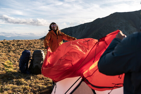 Joyful friends sharing effort while finishing tent together