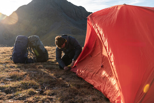 Thoughtful camper building temporary refuge against vast mountain space