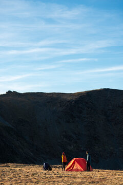 Minimalist alpine landscape framing friends setting camp at dusk
