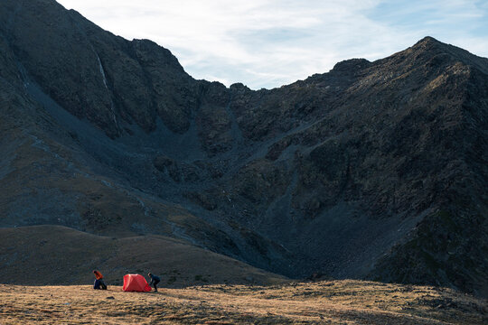 Remote mountain plateau with campers assembling shelter together