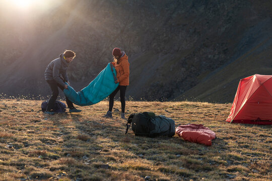 Adventurous friends coordinating sleeping bags at remote campsite