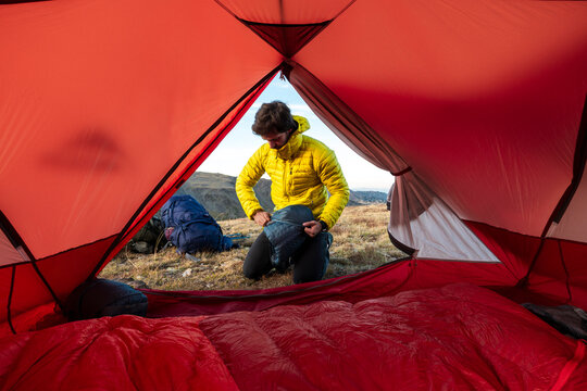 Dedicated hiker preparing sleeping system inside alpine tent