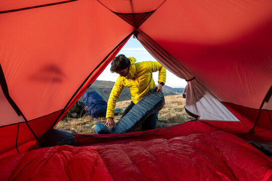 Determined adventurer unfolding sleeping mat in remote tent