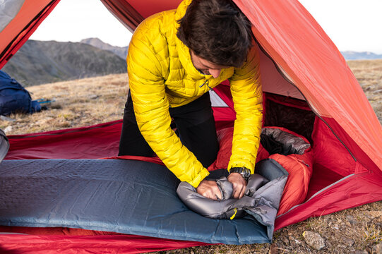Dedicated mountaineer finalizing sleeping pad inflation inside tent