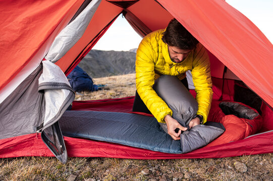Focused camper tightening air bag while inflating sleeping pad