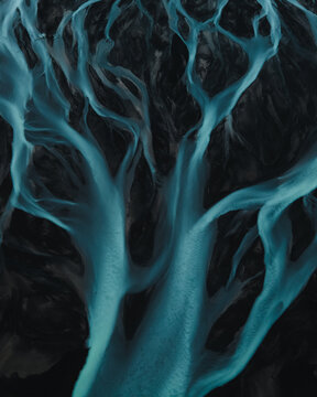 Aerial view of glacial rivers weaving through the stark landscape, a symphony of turquoise veins against the dark earth, Rangarthing eystra, Iceland.