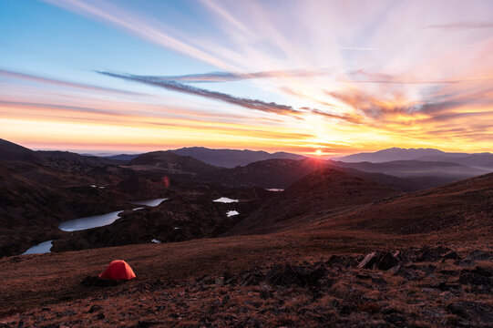 Remote mountain campsite facing expansive sunrise over alpine lakes