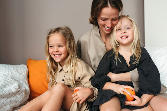 Happy Mother Embracing Daughters on the Bed