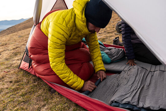 Determined hiker compressing sleeping pad inside mountain shelter