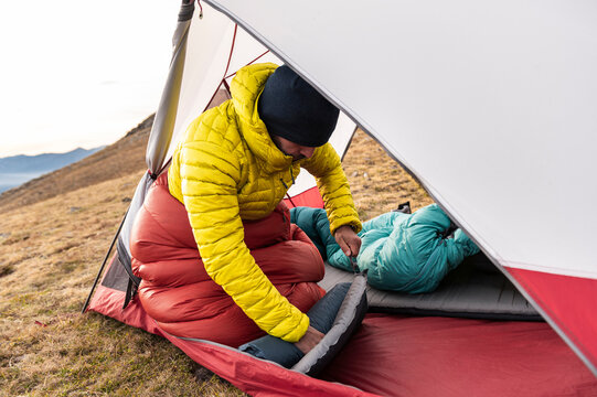 Experienced camper packing sleeping pad inside lightweight tent