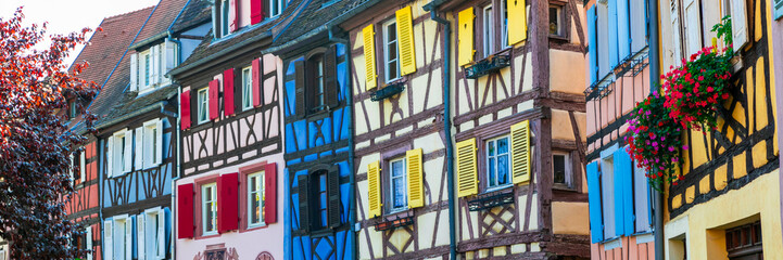 Naklejka premium Close up of Traditional Alsatian Half Timbered Houses in Colmar with Colorful Walls & Wooden Shutters and Floral Window Decor Authentic Old World Charm, Alsace France
